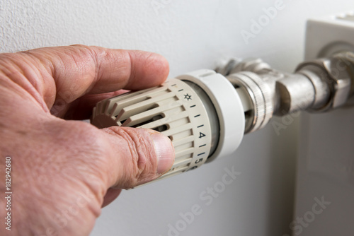 Closeup on man's hand adjusting thermostat valve