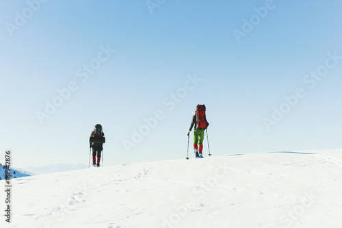 Winter hike in the mountains, two men are walking along the snow ridge.