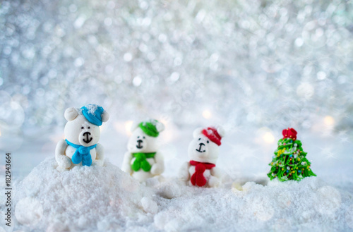 Three sugar candy bears in the snow on bokeh background with copy space for season greeting Merry Christmas or Happy New Year. Selective focus