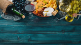 A large assortment of cheeses, wine, honey, nuts and spices, on a blue wooden table. Top view. Free space for text.