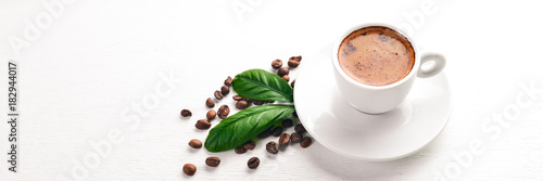 A cup of coffee and coffee beans on a wooden background. Top view. Free space for text.