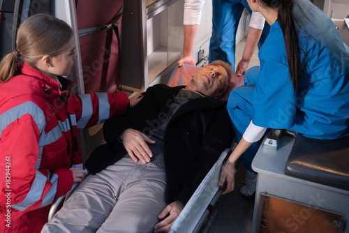 cropped image of paramedics moving unconscious man into ambulance