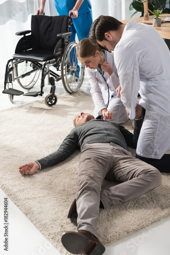 female doctor checking unconscious man palpitation with stethoscope