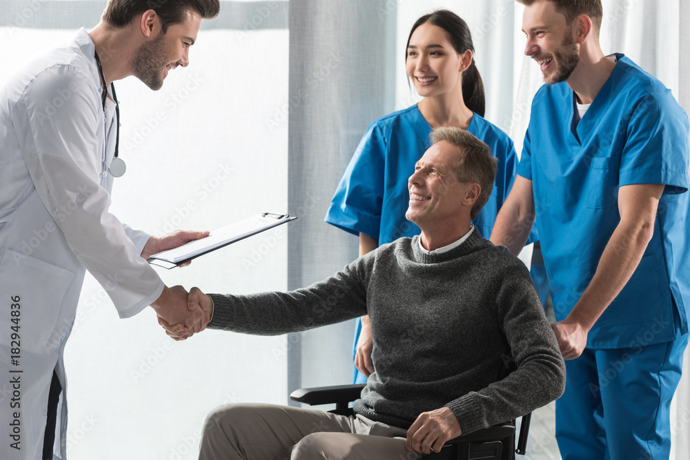 smiling doctor and patient on wheelchair shaking hands smiling doctor and patient on wheelchair shaking hands
