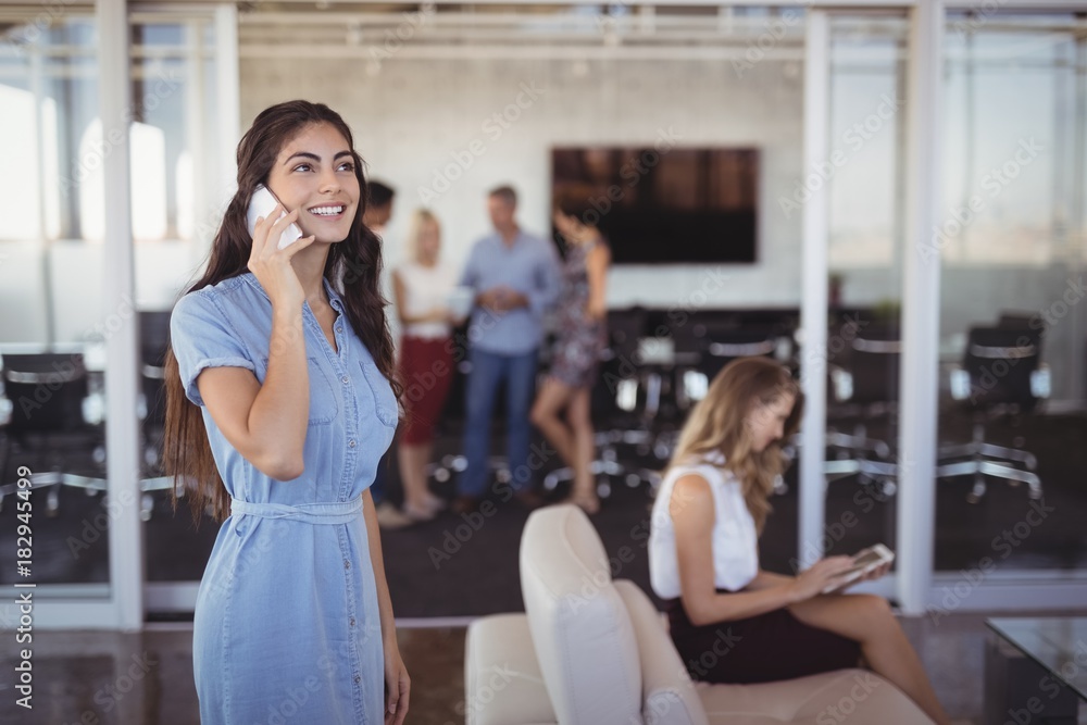 Obraz premium Young businesswoman talking on mobile phone at creative office