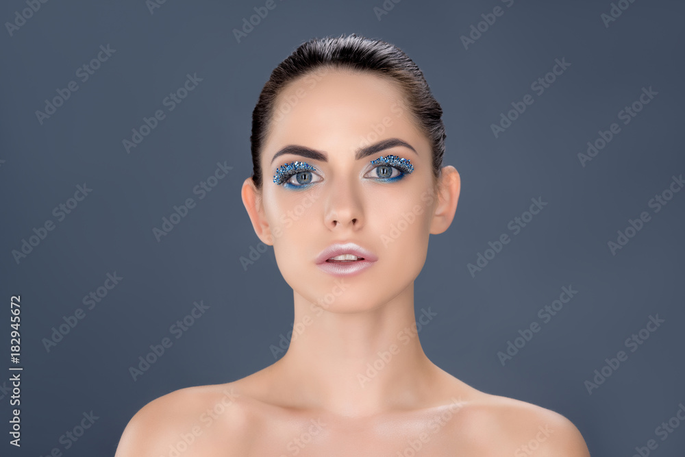 portrait of beautiful naked woman with winter makeup with glitter, isolated on grey portrait of beautiful naked woman with winter makeup with glitter, isolated on grey