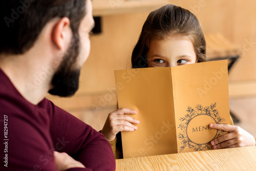cropped image of daughter looking out from restaurant menu