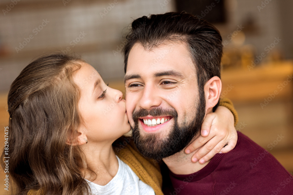 portrait of daughter kissing smiling father in cafe portrait of daughter kissing smiling father in cafe