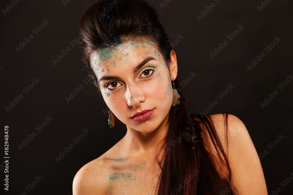 Stunning brunette with blue sparkles on her face posing in the studio looks like a fish Stunning brunette with blue sparkles on her face posing in the studio looks like a fish
