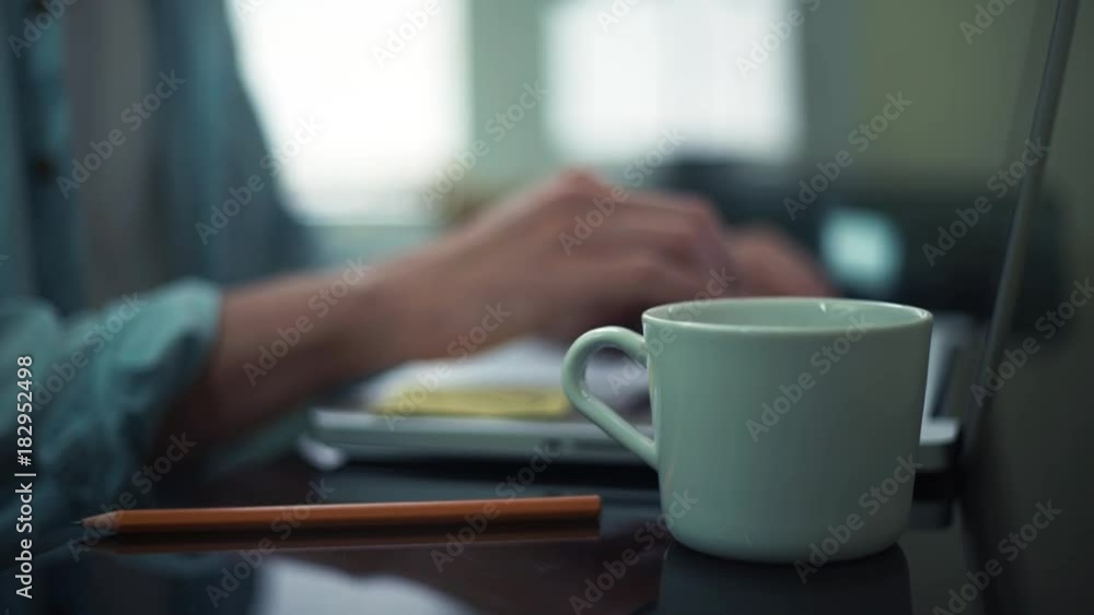 Male hands taking white cup from the desk. Guy using laptop at the office Male hands taking white cup from the desk. Guy using laptop at the office