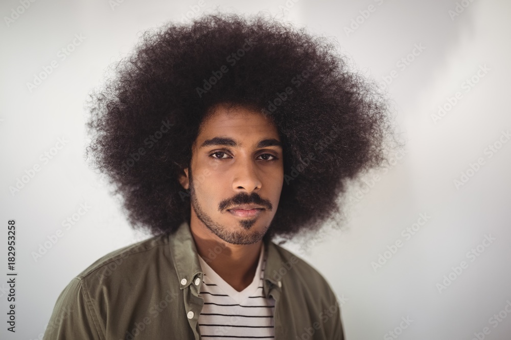 Portrait of confident businessman against wall in office