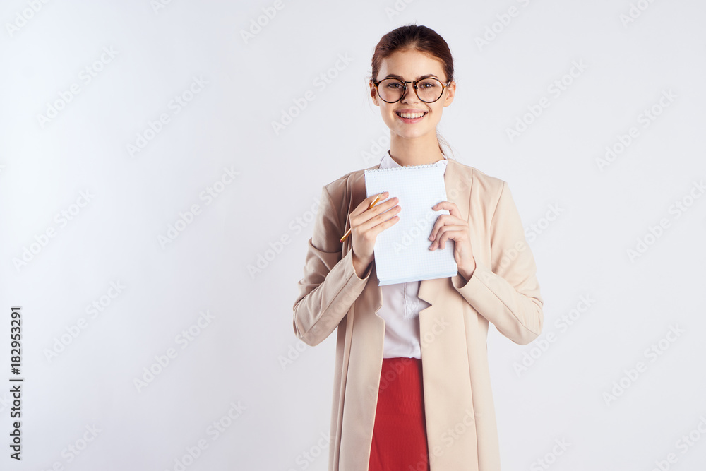 Beautiful young woman with glasses on a light background holds a paper, teacher Beautiful young woman with glasses on a light background holds a paper, teacher