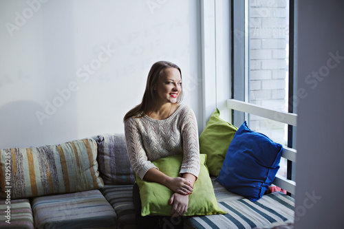 Wallpaper Mural Young woman sitting on striped sofa and looking out the window. Torontodigital.ca