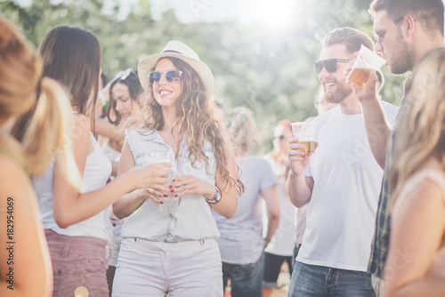 Group of people talking and drinking while standing at outdoor party