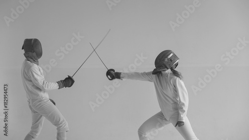 Two fencers having break after training attack exercises in fencing in studio indoors