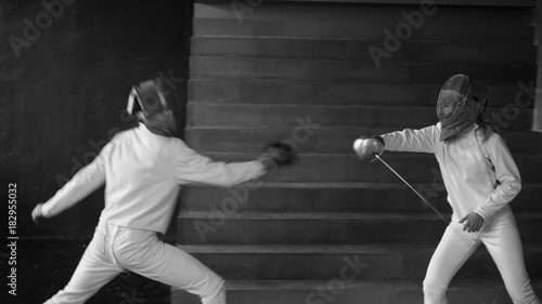 Two fencers man and woman have fencing match indoors