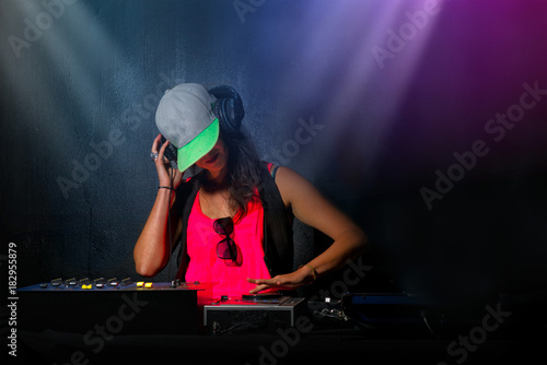 Glamorous girl deejay at work mixing sound on her console at a p