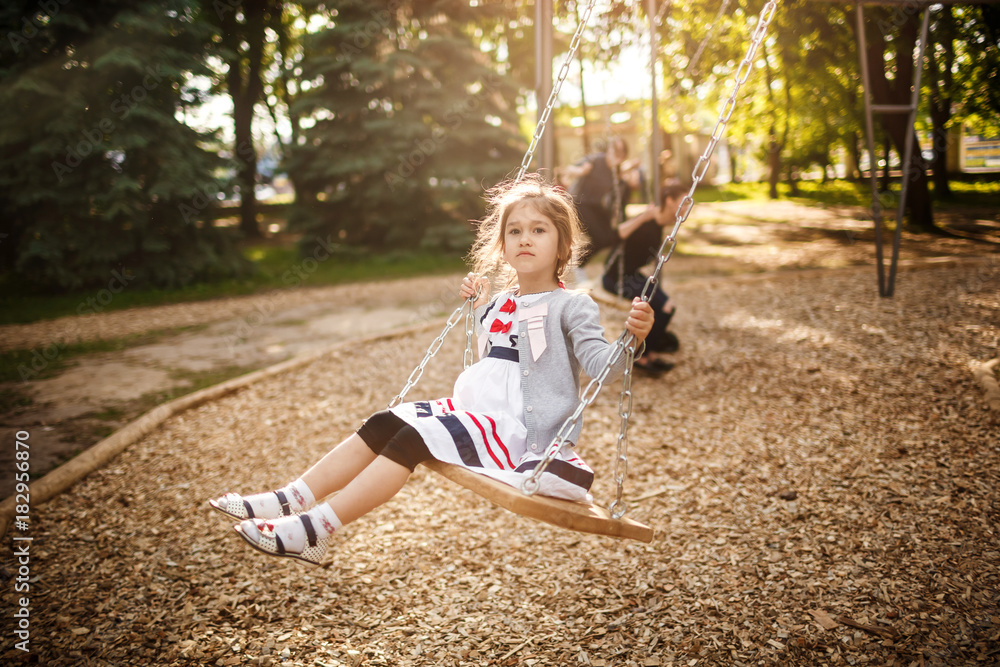 Cute little girl on a swing. Smiling child playing outdoors in summer. Cute little girl on a swing. Smiling child playing outdoors in summer.