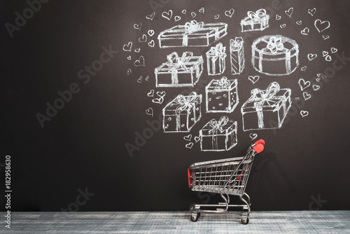 Shopping cart and presents on chalkboard. The drawn hearts and gift boxes puting in a basket Creative concept