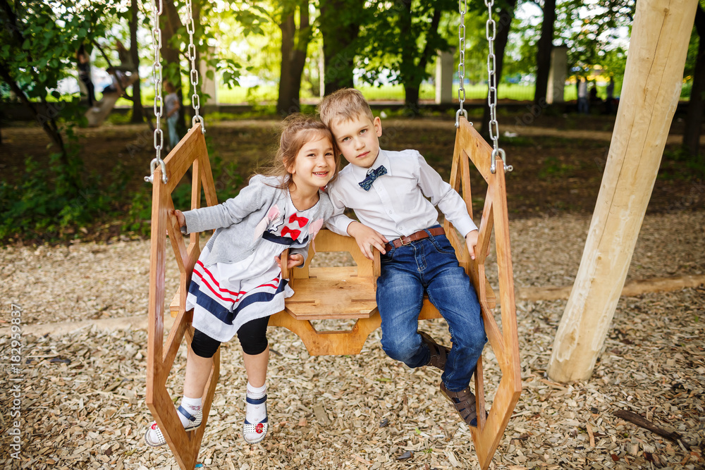Boy and girl on a swing. Children playing outdoors in summer. Boy and girl on a swing. Children playing outdoors in summer.
