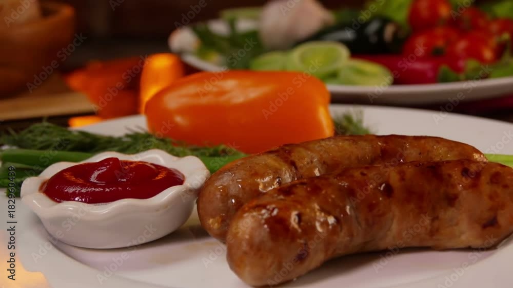 Hands put on the table a plate of dinner with grilled sausage on a background of a burning fireplace Hands put on the table a plate of dinner with grilled sausage on a background of a burning fireplace