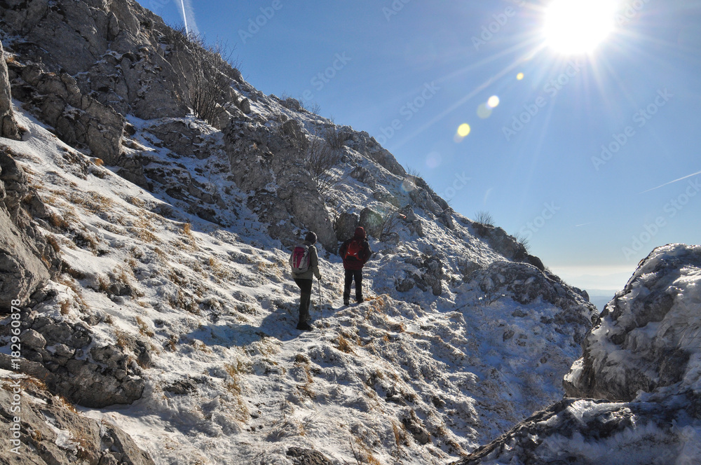 Couple of mountaineers hiking on snowy mountain into the sun. Climbers high in snowy mountains