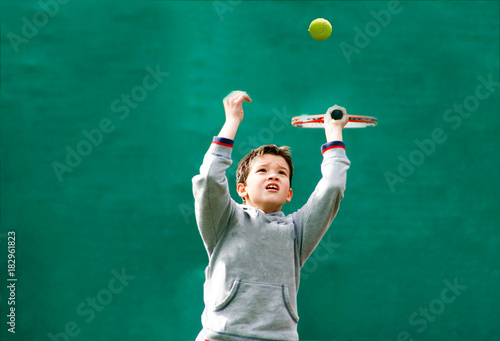 Little tennis player on a blurred green background © Stratos Giannikos