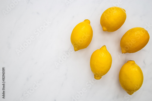 Bunch of lemons on white marble background with copy space
