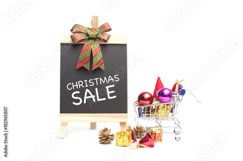 Chalkboard written with text Christmas SALE with mini shopping cart and christmas accessories isolated over white.