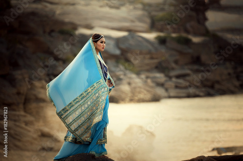 Portrait woman wearing Iran or Arab traditional dress standing on sand riverside photo