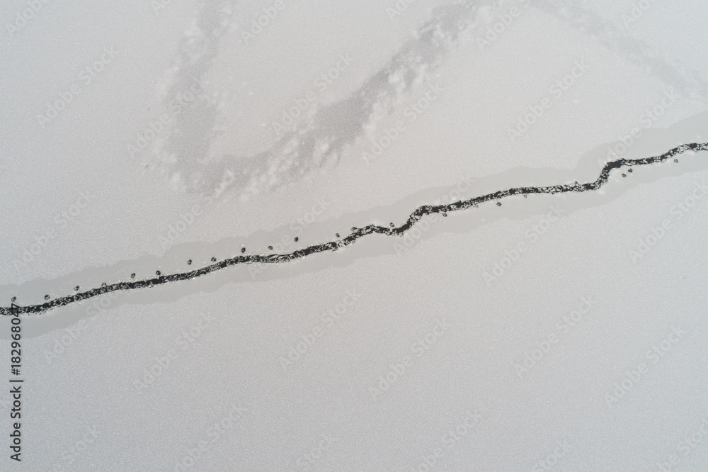 Drone view on winter lake with cracked ice