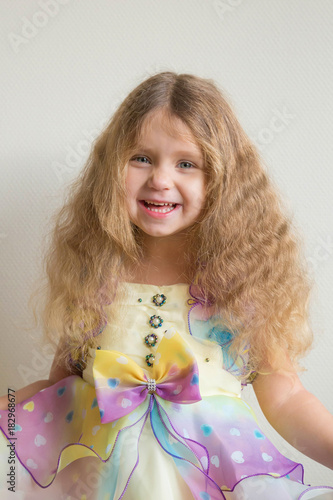 Beautiful smiling little girl with long blond curly hair. photo