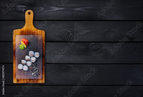 Classic sushi roll with shrimp on a wooden board. Top view. Black wooden background