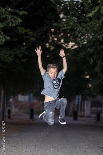 Charming stylish boy jumping at street