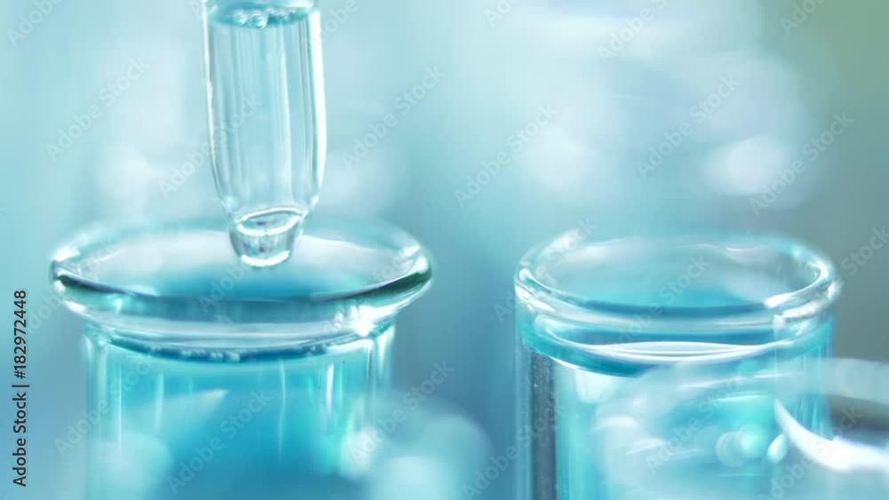 In a laboratory, a scientist with a pipette analyzes a blue liquid to extract the DNA and molecules in the test tubes. Doctor working with liquid. In a laboratory, a scientist with a pipette analyzes a blue liquid to extract the DNA and molecules in the test tubes. Doctor working with liquid.