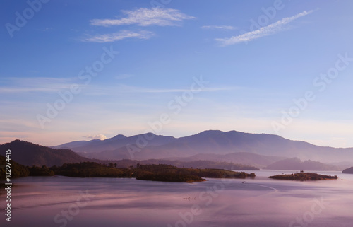 beautiful landscape with the surface of the sea with mountains in the background in the pink dawn