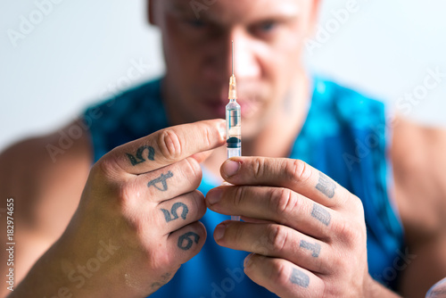 Close up of a syringe in hands of a bodybuilder photo