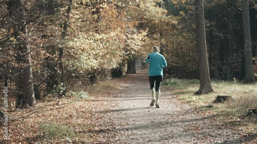 Rear Back View of Man Walking or Running In Autumn Forest Park. Healthy Lifestyle. photo