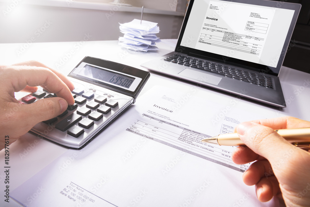 Businessperson's Hand Calculating Invoice Businessperson's Hand Calculating Invoice