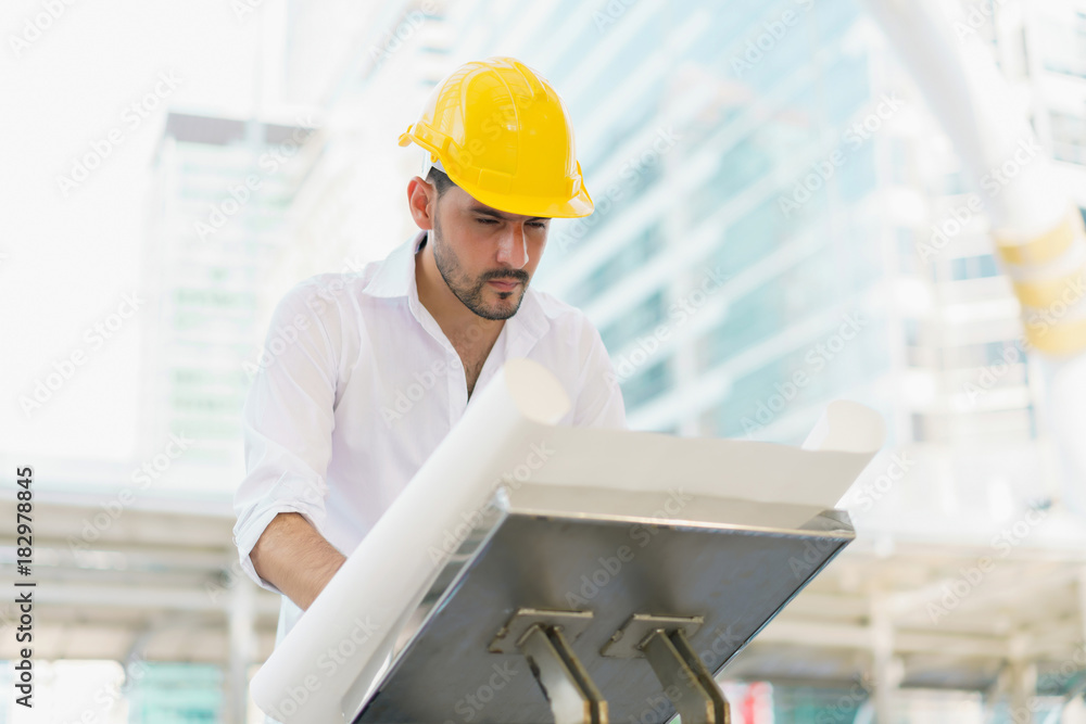 Engineer man wearing safety helmet and hold blueprint document at construction site. concept of work office, security consult, job control, development and business process. Engineer man wearing safety helmet and hold blueprint document at construction site. concept of work office, security consult, job control, development and business process.