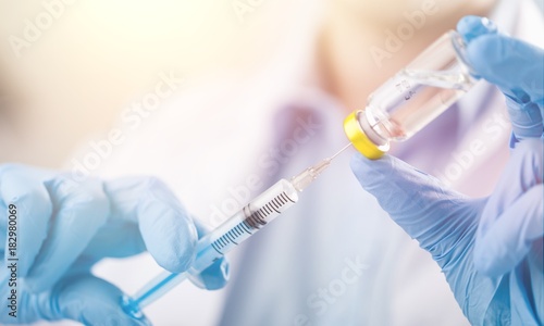 Hand holding syringe and vaccine.