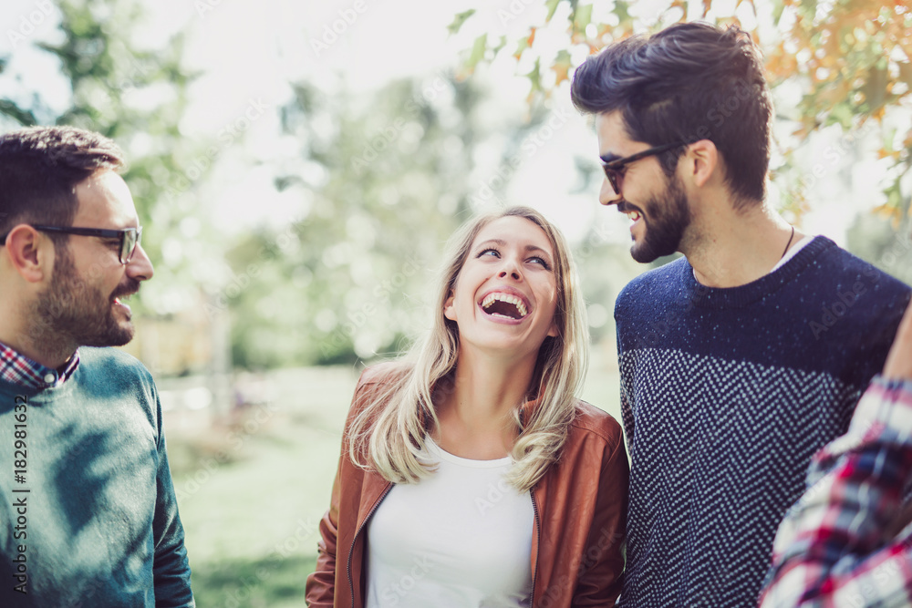 Naklejka premium Image of four happy smiling young friends walking outdoors in the park. Love, happiness and friendship concept