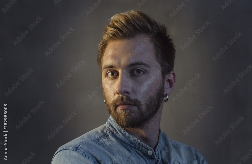 Portrait of bearded man face with stylish hairstyle on head and earring in ear Portrait of bearded man face with stylish hairstyle on head and earring in ear