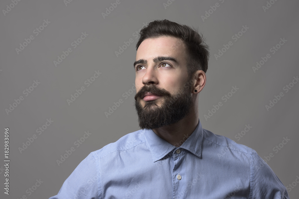 Obraz premium Confident young handsome stylish business man looking up at copyspace against gray studio background. Idea concept.