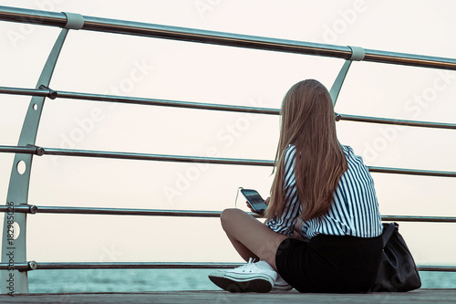Girl sitting on pier and lookingat the sea photo