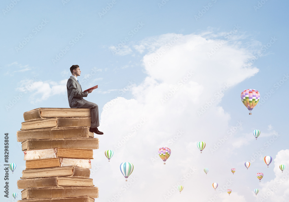 Man student reading book and aerostats flying around in air