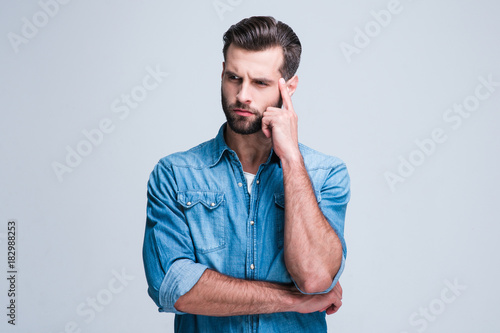 What have I forgot? Handsome young man looking confused while standing against white background