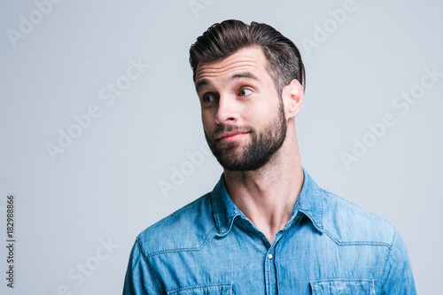 Nice thing! Portrait of handsome young man looking away while standing against white background © MARIIA