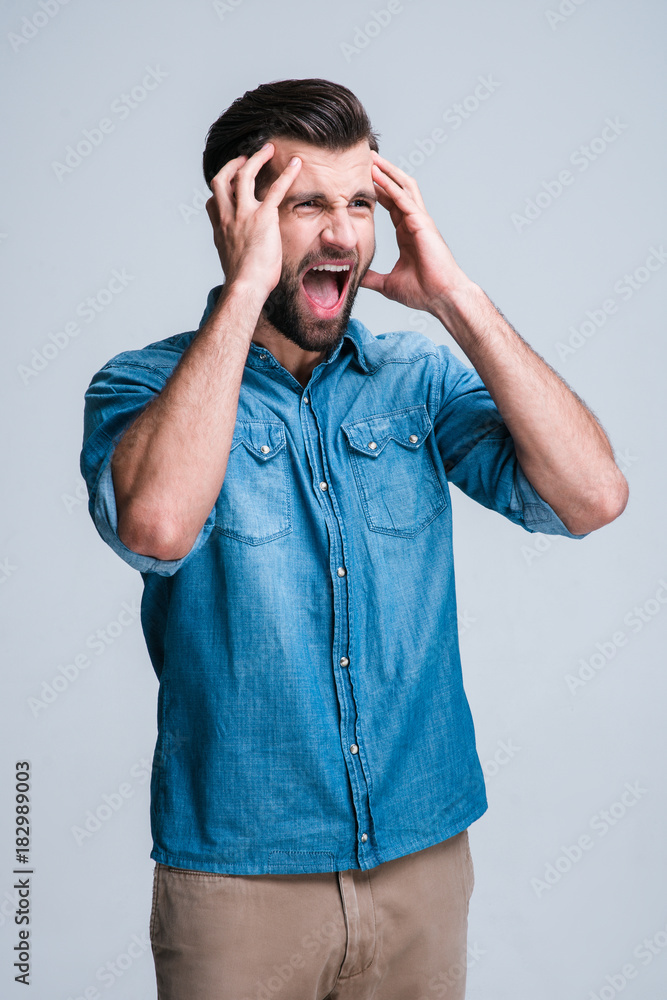 Real problems. Handsome young man keeping mouth open and looking frustrated while standing against white background Real problems. Handsome young man keeping mouth open and looking frustrated while standing against white background