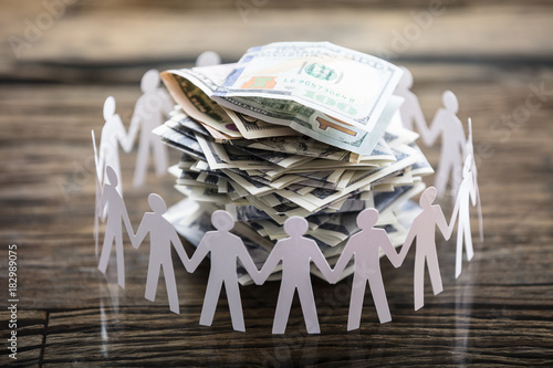 Paper Cut Out Human Figure Surrounding Stacked Banknotes